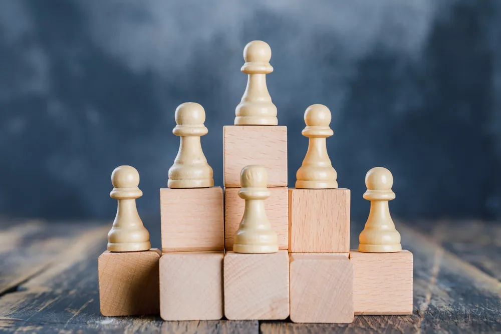Chess pawns standing on wooden blocks of rising height